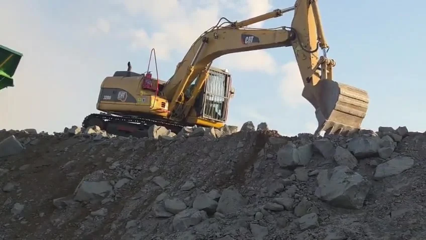 CAT excavator working over blasted quarry rock